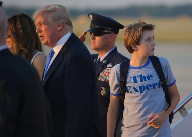 Barron Trump (R), the son of US President Donald Trump (2L) and First Lady Melania Trump (L) look back at Air Force One upon arrival at Andrews Air Force Base in Maryland on June 11, 2017. Trump is returning to Washington, DC after spending the weekend at this Bedminster, New Jersey golf club. / AFP PHOTO / MANDEL NGAN