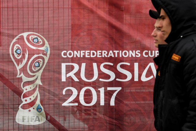 Funcionarios de seguridad pasan frente a un banner de la Copa Confederaciones Rusia 2017 (Foto: AFP)