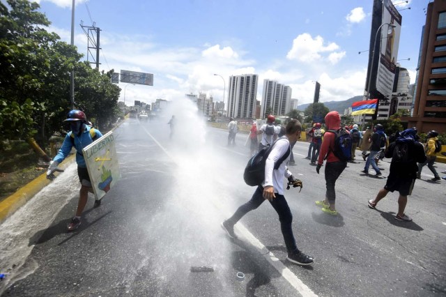 Opposition activists clash with riot police whilst protesting against the government of President Nicolas Maduro along the Francisco Fajardo motorway in Caracas on June 19, 2017. Venezuela's Supreme Court on Friday rejected a bid to put on trial several senior judges accused of favoring embattled President Nicolas Maduro as he clings to power in the face of deadly unrest. / AFP PHOTO / JUAN BARRETO