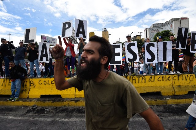 An opposition activist demonstrates against the government of Venezuelan President Nicolas Maduro in Caracas on June 24, 2017, in front of the Francisco de Miranda air force base near the place where a young man was shot dead by police during an anti-government rally two days ago. A political and economic crisis in the oil-producing country has spawned often violent demonstrations by protesters demanding Maduro's resignation and new elections. The unrest has left 75 people dead since April 1. / AFP PHOTO / Juan BARRETO