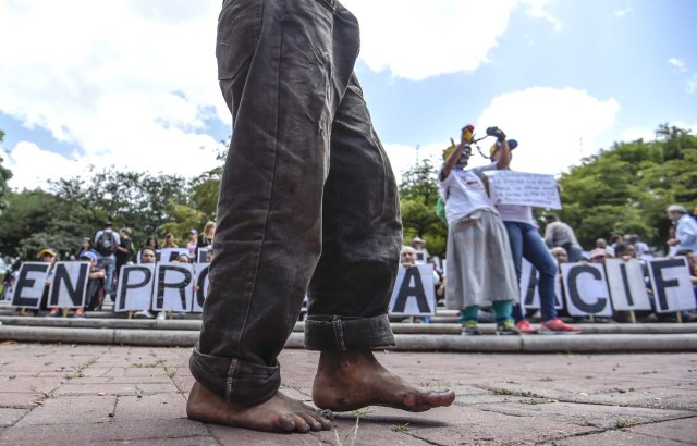 A boy passes in front of demonstrators protesting in Caracas on June 27, 2017. / AFP PHOTO / JUAN BARRETO