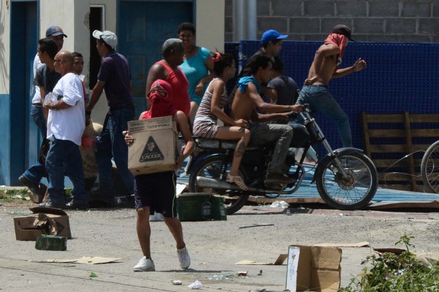 People carry stolen merchandise during lootings in Maracay, Aragua State, Venezuela on June 27, 2017. A political and economic crisis in the oil-producing country has spawned often violent demonstrations by protesters demanding President Nicolas Maduro's resignation and new elections. The unrest has left 76 people dead since April 1. / AFP PHOTO / Federico PARRA