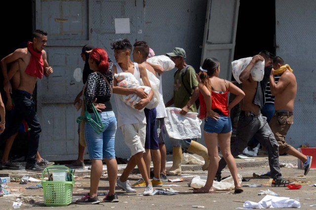 People carry stolen merchandise during lootings in Maracay, Aragua State, Venezuela on June 27, 2017. A political and economic crisis in the oil-producing country has spawned often violent demonstrations by protesters demanding President Nicolas Maduro's resignation and new elections. The unrest has left 76 people dead since April 1. / AFP PHOTO / Federico PARRA