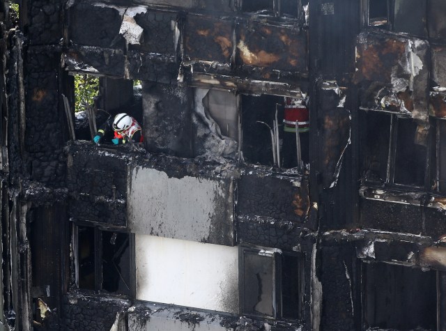A firefighter examines material in a tower block severely damaged by a serious fire, in north Kensington, West London, Britain June 14, 2017. REUTERS/Neil Hall