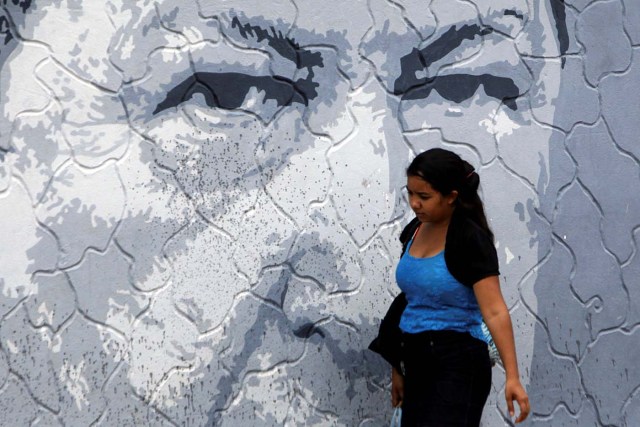 A woman walks past a mural depicting Venezuela's late President Hugo Chavez in Sabaneta, Venezuela June 13, 2017. Picture taken June 13, 2017. REUTERS/Carlos Eduardo Ramirez