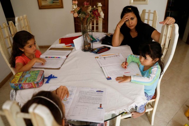 Aldrina Valenzuela (C), helps her daughter Renata (R) and her nieces Carlota (L) and Carmen, to do the homework at her mother's house on a day of protests in Caracas, Venezuela June 14, 2017. Picture taken June 14, 2017. REUTERS/Carlos Garcia Rawlins
