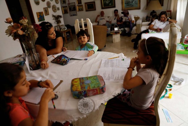 Aldrina Valenzuela (L), helps her daughter Renata (C) and her nieces Carlota (L) and Carmen, to do the homework at her mother's house on a day of protests in Caracas, Venezuela June 14, 2017. Picture taken June 14, 2017. REUTERS/Carlos Garcia Rawlins