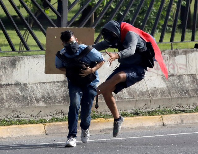 REFILE - ADDING INFORMATION A protester covers fellow protester David Jose Vallenilla (L), who was fatally injured, outside an air force base during clashes with riot security forces at a rally against Venezuelan President Nicolas Maduro’s government in Caracas, Venezuela June 22, 2017. REUTERS/Carlos Garcia Rawlins