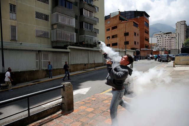 A demonstrator throws back a tear gas grenade while clashing with riot security forces during a rally against Venezuela's President Nicolas Maduro's Government in Caracas, Venezuela June 23, 2017. REUTERS/Ivan Alvarado