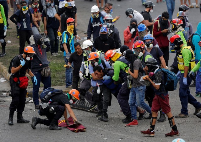An injured demonstrator is carried away by paramedics as others clash with riot security forces during a rally against Venezuela's President Nicolas Maduro's Government in Caracas, Venezuela, June 24, 2017. REUTERS/Ivan Alvarado