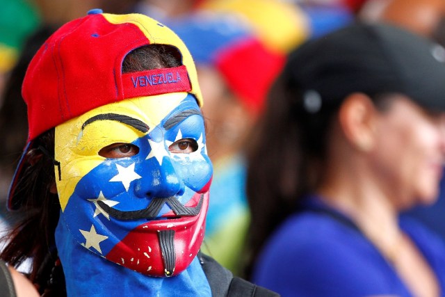 A demonstrator wears a mask painted with Venezuelan flag colors during a rally against Venezuela's President Nicolas Maduro's Government in Caracas, Venezuela, June 24, 2017. REUTERS/Christian Veron