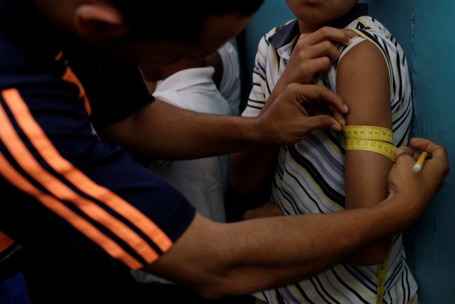 A teacher measures a child's arm as part of a health program of the Miranda state government at a school in Caracas, Venezuela March 25, 2017. Picture taken March 25, 2017. REUTERS/Marco Bello