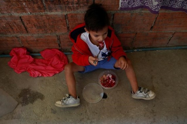 Luis Berrios se sienta en el suelo mientras come su comida en su choza en Caracas, Venezuela. 26 de junio 2017. De la mano de su mamá, Samuel Becerra ingresó a fines de marzo al hospital pediátrico J.M. De Los Ríos, en Caracas, para hacerse una hemodiálisis de rutina. Estando internado, el niño de 12 años contrajo una infección que acabó con su vida, junto a la de otros tres pequeños.REUTERS/Marco Bello - RTS19011