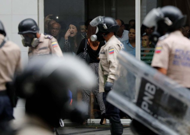 A woman gestures from inside a building as police detain protesters (not pictured) during a rally against Venezuela's President Nicolas Maduro's government in Caracas, Venezuela June 29, 2017. REUTERS/Carlos Garcia Rawlins