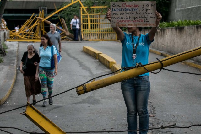 CAR01. CARACAS (VENEZUELA), 14/06/2017.- Una mujer protesta en la entrada de las residencias Los Verdes ubicadas en el oeste de Caracas (Venezuela) hoy, miércoles 14 de junio de 2017. El oeste de Caracas fue sacudido anoche por la policía militarizada en un operativo que terminó, según el Gobierno venezolano, con la detención de 23 "terroristas" mientras que opositores aseguran hoy que se trató de una acción "terrible" en la que funcionarios causaron destrozos materiales y dispararon a mascotas. EFE/Miguel Gutiérrez