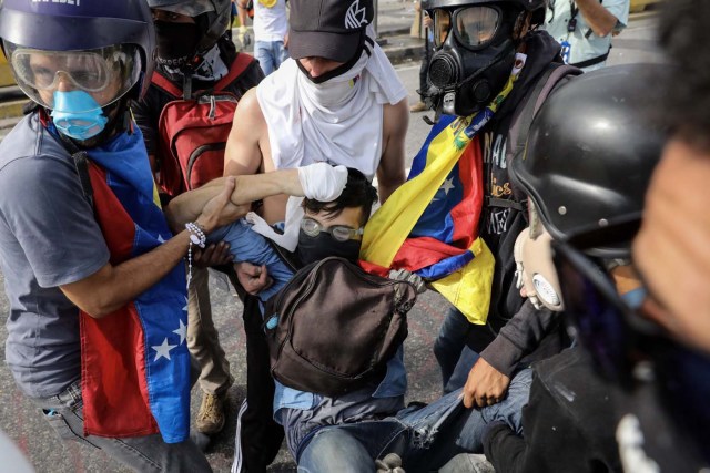 VEN05. CARACAS (VENEZUELA), 22/06/2017.- Un grupo de manifestantes auxilia al joven David José Vallenilla (c), de 22 años, luego de recibir un disparo de un miembro de la Guardia Nacional Bolivariana (GNB) hoy, jueves 22 de junio de 2017, en las inmediaciones de la bases aérea militar La Carlota, en Caracas (Venezuela). El Ministerio Público (MP) de Venezuela informó hoy del fallecimiento de Vallenilla, que recibió un disparo durante una manifestación opositora en Caracas. Con este deceso la Fiscalía cuenta 75 fallecidos según los datos corregidos y actualizados del organismo en sus informes sobre la oleada de protestas que inició el pasado 1 de abril en el país. EFE/Miguel Gutiérrez