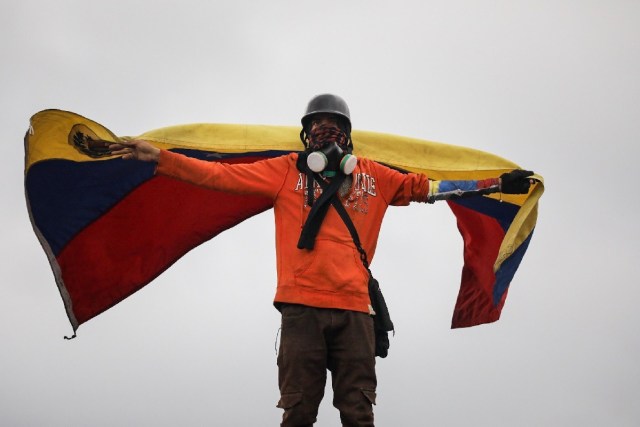 CAR22. CARACAS (VENEZUELA), 24/06/2017.- Un hombre que usa máscara de gas ondea una bandera venezolana sobre sus hombros durante una manifestación denominada "Venezuela le da un mensaje a la FAN (Fuerza Armada)" hoy, sábado 24 de junio de 2017, en Caracas (Venezuela). La oposición venezolana se moviliza hoy hasta las bases militares en Caracas y varios estados del país, mientras el chavismo marcha para conmemorar los 196 años de la Batalla de Carabobo, una acción militar decisiva en la independencia del país caribeño, y por el Día del Ejército Bolivariano. EFE/Miguel Gutiérrez