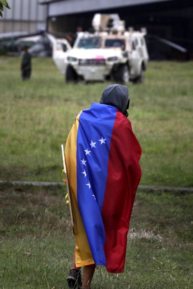CAR28. CARACAS (VENEZUELA), 24/06/2017.- Un hombre que usa máscara de gas envuelve su cuerpo con una bandera venezolana durante una manifestación denominada "Venezuela le da un mensaje a la FAN (Fuerza Armada)" hoy, sábado 24 de junio de 2017, en Caracas (Venezuela). La oposición venezolana se moviliza hoy hasta las bases militares en Caracas y varios estados del país, mientras el chavismo marcha para conmemorar los 196 años de la Batalla de Carabobo, una acción militar decisiva en la independencia del país caribeño, y por el Día del Ejército Bolivariano. EFE/Miguel Gutiérrez