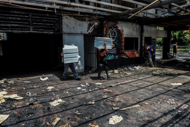 Los saqueadores llevan mercancía en un supermercado ya saqueado en Maracay, estado de Aragua, Venezuela, el 27 de junio de 2017. / AFP PHOTO / FEDERICO PARRA
