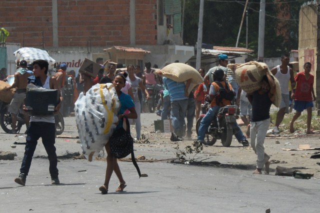 La gente lleva mercancía robada durante saqueos en Maracay, estado de Aragua, Venezuela el 27 de junio de 2017 / AFP PHOTO / Federico PARRA
