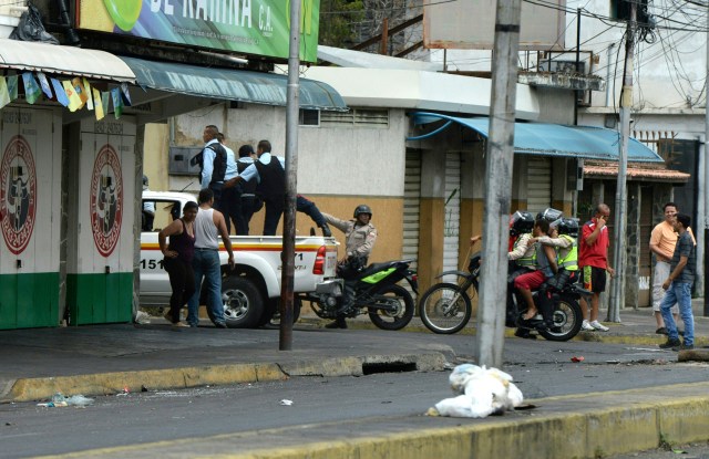 Contenido gráfico / La policía lleva a un hombre bajo custodia (en la motocicleta) durante saqueos en Maracay, Venezuela, el 27 de junio de 2017. / AFP PHOTO / Federico Parra