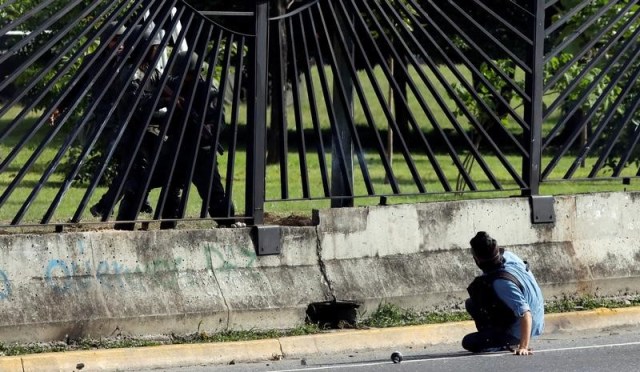 Un miembro de las fuerzas de seguridad antidisturbios apunta un arma no identificada a través de la cerca de una base aérea en Caracas a un manifestante de la oposición, durante enfrentamientos en medio de protestas contra el Gobierno del presidente venezolano Nicolás Maduro, Venezuela, 22 de junio de 2017. REUTERS/Carlos Garcia Rawlins