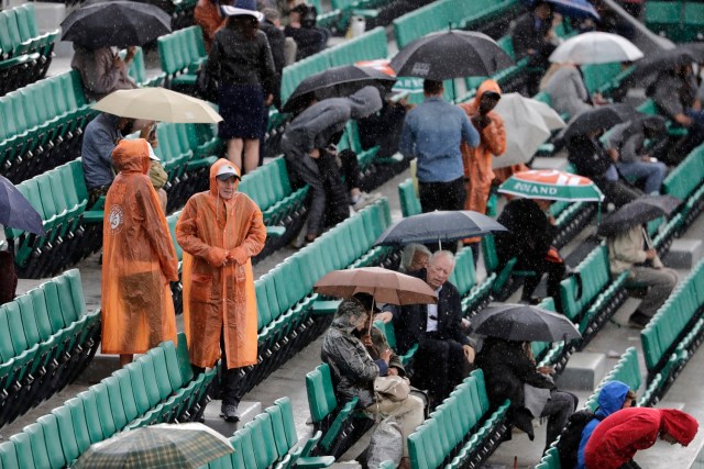 A picture taken on June 6, 2017 in Paris shows visitors with umbrellas waiting under the rain for a match to resume on the Philippe Chatrier court during a downpour at the Roland Garros 2017 French tennis Open.  / AFP PHOTO / Thomas SAMSON
