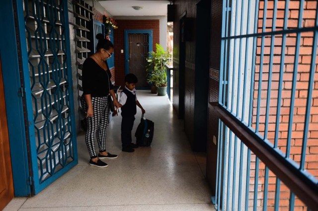 Karelys Rojas and his son wait in the hall on their way to school at the San Juan neighborhood in Caracas, on June 27, 2017. / AFP PHOTO / FEDERICO PARRA / TO GO WITH AFP STORY by ALEXANDER MARTINEZ