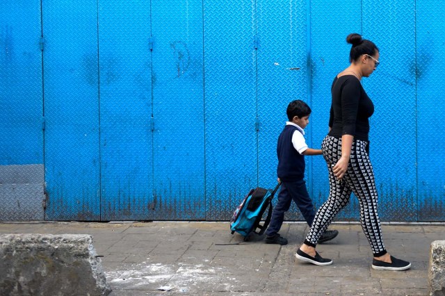 Karelys Rojas and his son walk to school at the San Juan neighborhood in Caracas, on June 27, 2017. / AFP PHOTO / FEDERICO PARRA / TO GO WITH AFP STORY by ALEXANDER MARTINEZ