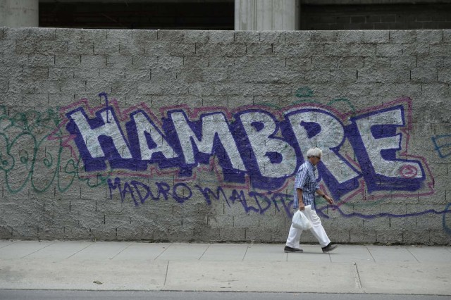 Un hombre pasa frente a un mural contra el gobierno de Maduro en Caracas  / AFP PHOTO / FEDERICO PARRA