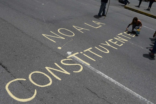 Venezuelan opposition activists write "No to the Constituent (Assembly)" during an anti-government protest in Caracas on July 10, 2017. Venezuela hit its 100th day of anti-government protests Sunday, amid uncertainty over whether the release from prison a day earlier of prominent political prisoner Leopoldo Lopez might open the way to negotiations to defuse the profound crisis gripping the country. / AFP PHOTO / FEDERICO PARRA