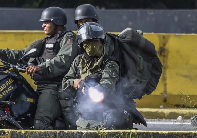 Members of the National Guard charge on opposition activists during protests against Venezuelan President Nicolas Maduro in Caracas on July 10, 2017. Venezuela hit its 100th day of anti-government protests Sunday, amid uncertainty over whether the release from prison a day earlier of prominent political prisoner Leopoldo Lopez might open the way to negotiations to defuse the profound crisis gripping the country. / AFP PHOTO / JUAN BARRETO