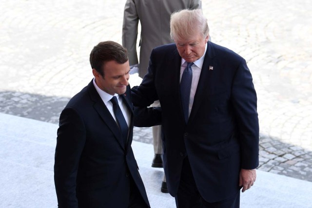 French President Emmanuel Macron (L) gestures next to US President Donald Trump during the annual Bastille Day military parade on the Champs-Elysees avenue in Paris on July 14, 2017. The parade on Paris's Champs-Elysees will commemorate the centenary of the US entering WWI and will feature horses, helicopters, planes and troops. / AFP PHOTO / ALAIN JOCARD