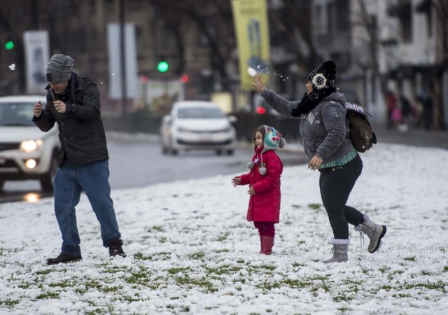 People play with snow in Santiago on July 15, 2017.  An unusual snowfall --the first of such intensity since 2007-- surprised the inhabitants of the Chilean capital, causing a few power cuts and minor traffic jams, in particular in the eastern areas of the capital, the closest to the Andes mountain range. / AFP PHOTO / Martin BERNETTI