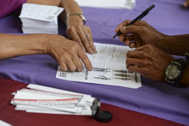 A man marks his ballot on July 16, 2017 in Caracas, in an opposition-organized vote to measure public support for President Nicolas Maduro's plan to rewrite the constitution, against a backdrop of worsening political violence . The authorities have refused to greenlight a vote that has been presented as an act of civil disobedience and supporters of Maduro are boycotting it. So voters seemed set to reject the president's controversial plan. / AFP PHOTO / Federico Parra