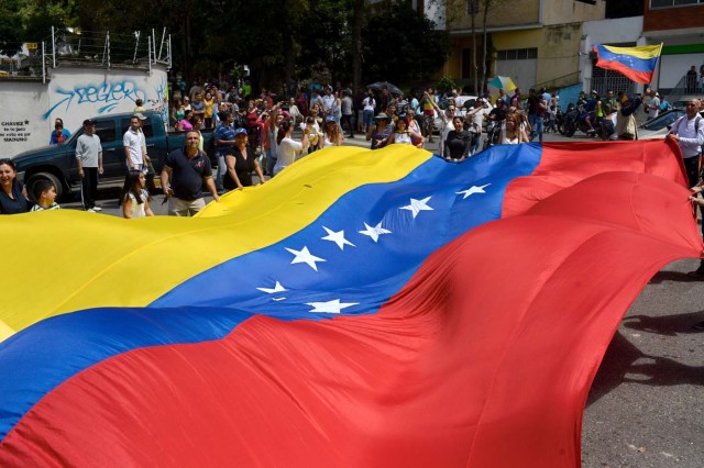 People gather in Caracas on July 16, 2017 during an opposition-organized vote to measure public support for President Nicolas Maduro's plan to rewrite the constitution. Authorities have refused to greenlight the vote that has been presented as an act of civil disobedience and supporters of Maduro are boycotting it. Protests against Maduro since April 1 have brought thousands to the streets demanding elections, but has also left 95 people dead, according to an official toll. / AFP PHOTO / FEDERICO PARRA