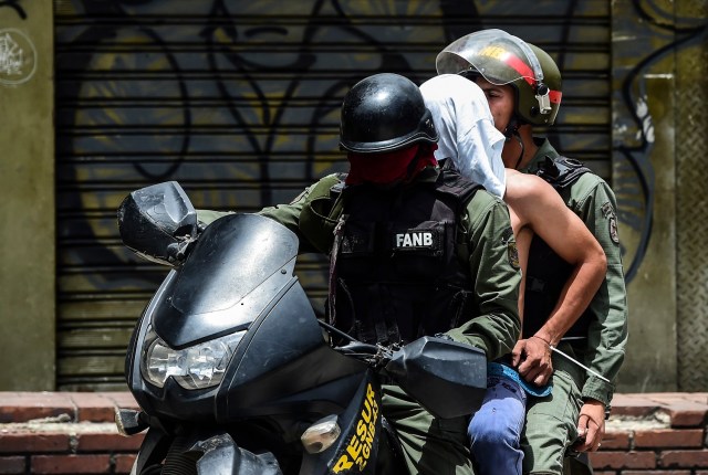 Los motociclistas de la Guardia Nacional llevan a un manifestante arrestado bajo custodia durante una protesta contra el gobierno en Caracas, el 20 de julio de 2017. Una huelga nacional de 24 horas se inició en Venezuela el jueves, en un intento de la oposición de aumentar la presión sobre el presionado presidente izquierdista Nicolás Maduro tras cuatro meses de manifestaciones callejeras mortales. / AFP PHOTO / RONALDO SCHEMIDT