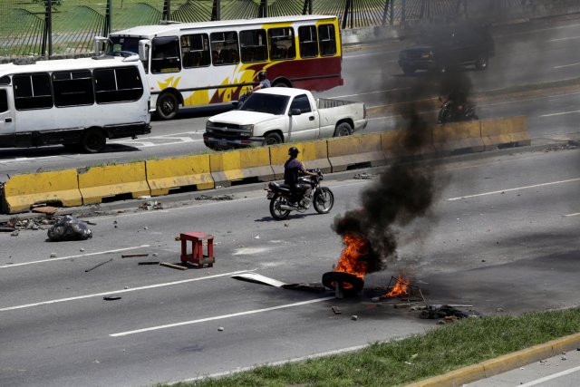 A man on a motorcycle rides near the remains of a fire barricade built by opposition supporters rallying against Venezuela's President Nicolas Maduro's government, in Caracas, Venezuela July 4, 2017. REUTERS/Marco Bello