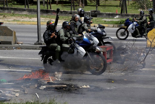 Riot security forces ride on their motorcycles past fire barricades built by opposition supporters rallying against Venezuela's President Nicolas Maduro's government, in Caracas, Venezuela July 4, 2017.  REUTERS/Marco Bello