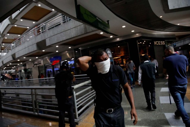 A man covers his face from tear gas inside a shopping mall as clashes between demonstrators and security forces occured on the streets during a rally against Venezuelan President Nicolas Maduro's government in Caracas, Venezuela, July 6, 2017. REUTERS/Carlos Garcia Rawlins