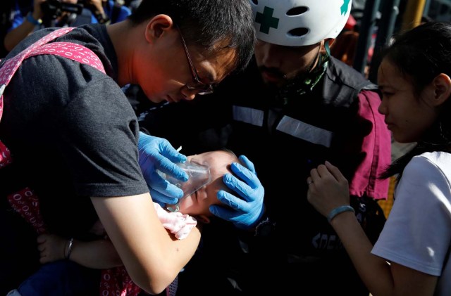 A baby gets medical attention outside a shopping mall after smoke from tear gas fired by security forces got inside of it during clashes at a rally against Venezuelan President Nicolas Maduro's government in Caracas, Venezuela, July 6, 2017. REUTERS/Carlos Garcia Rawlins