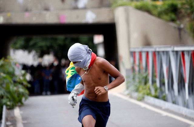 A masked demonstrator runs during clashes with security forces at a rally against Venezuelan President Nicolas Maduro's government in Caracas, Venezuela, July 6, 2017. REUTERS/Andres Martinez Casares