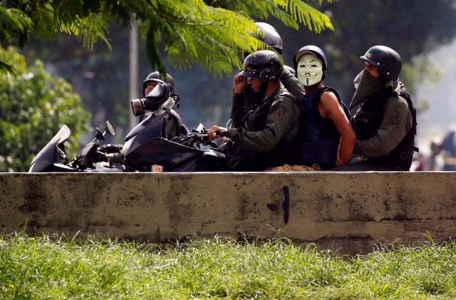 A demonstrator wearing a Guy Fawkes mask is detained by security forces during a protest against Venezuelan President Nicolas Maduro's government in Caracas, Venezuela July 10, 2017. REUTERS/Carlos Garcia Rawlins