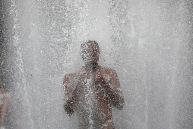 A man gets relief from hot weather as he cools off in a fountain in Washington Square Park in the Manhattan borough of New York City, U.S., July 13, 2017. REUTERS/Mike Segar