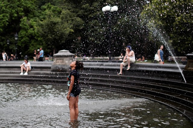 A woman gets relief from hot weather as she cools off in a fountain in Washington Square Park in the Manhattan borough of New York City, U.S., July 13, 2017. REUTERS/Mike Segar