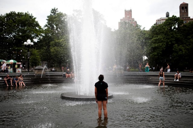 A woman gets relief from hot weather as she cools off in a fountain in Washington Square Park in the Manhattan borough of New York City, U.S., July 13, 2017. REUTERS/Mike Segar