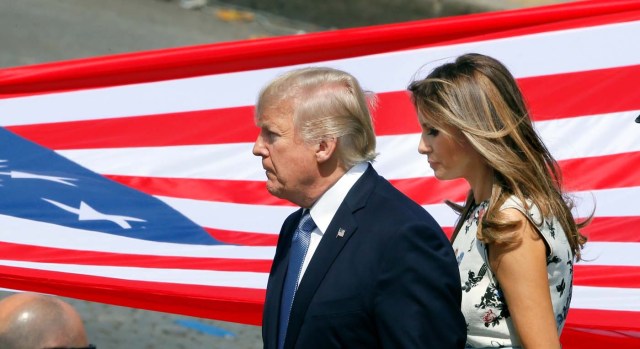 U.S. President Donald Trump and First Lady Melania Trump stand in front of the American flag at the end of the traditional Bastille Day military parade on the Champs-Elysees in Paris, France, July 14, 2017. REUTERS/Gonzalo Fuentes