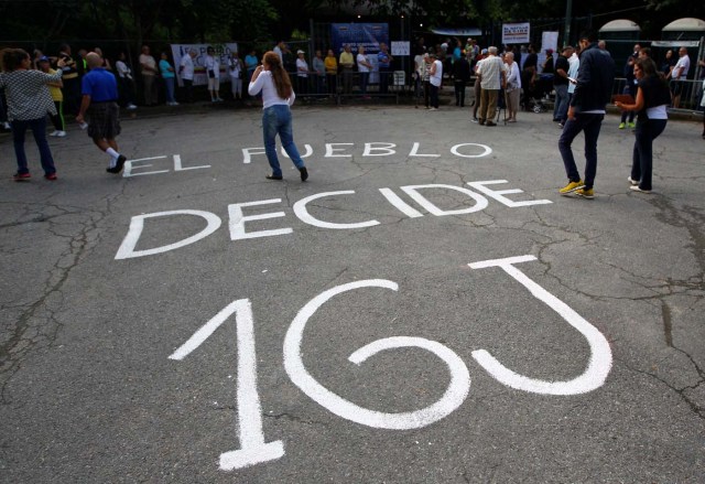 People gather at a polling station during an unofficial plebiscite against Venezuela's President Nicolas Maduro's government and his plan to rewrite the constitution, in Caracas, Venezuela July 16, 2017. The writing on the pavement reads: "The people decide 16J(uly)." REUTERS/Christian Veron