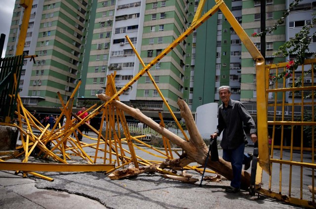 FILE PHOTO: A man walks through a broken main gate after opposition supporters and security forces clashed in and outside residential buildings on Tuesday according to residents, in Caracas, Venezuela June 14, 2017. REUTERS/Ivan Alvarado/File Photo