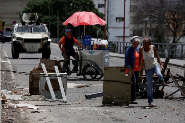 Las mujeres pasan por un cable utilizado para bloquear una calle durante una huelga convocada para protestar contra el gobierno del presidente venezolano Nicolás Maduro en Caracas, Venezuela, 20 de julio de 2017. REUTERS / Carlos Garcia Rawlins